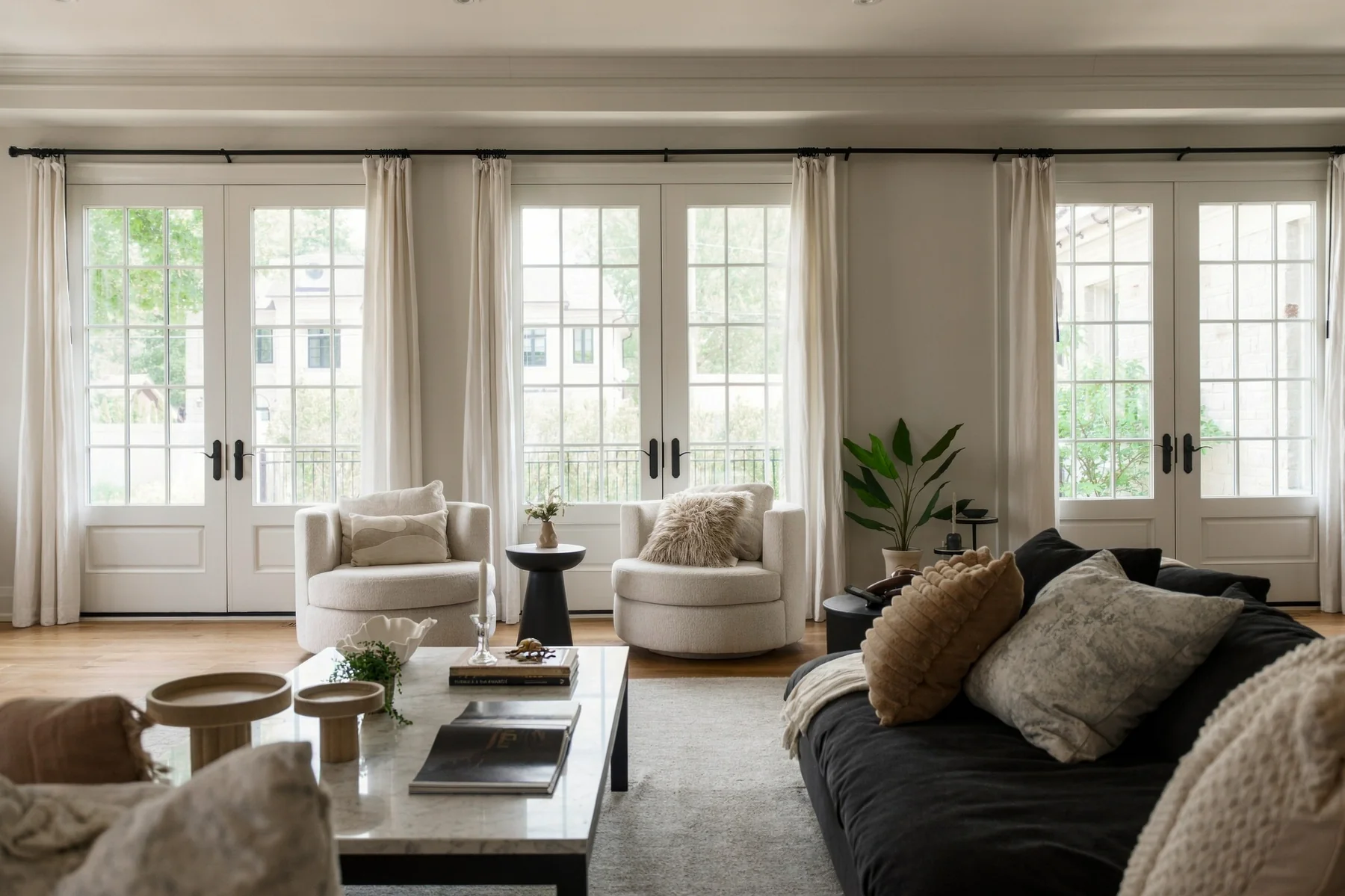 A living room with French doors, neutral furnishings and layered textures