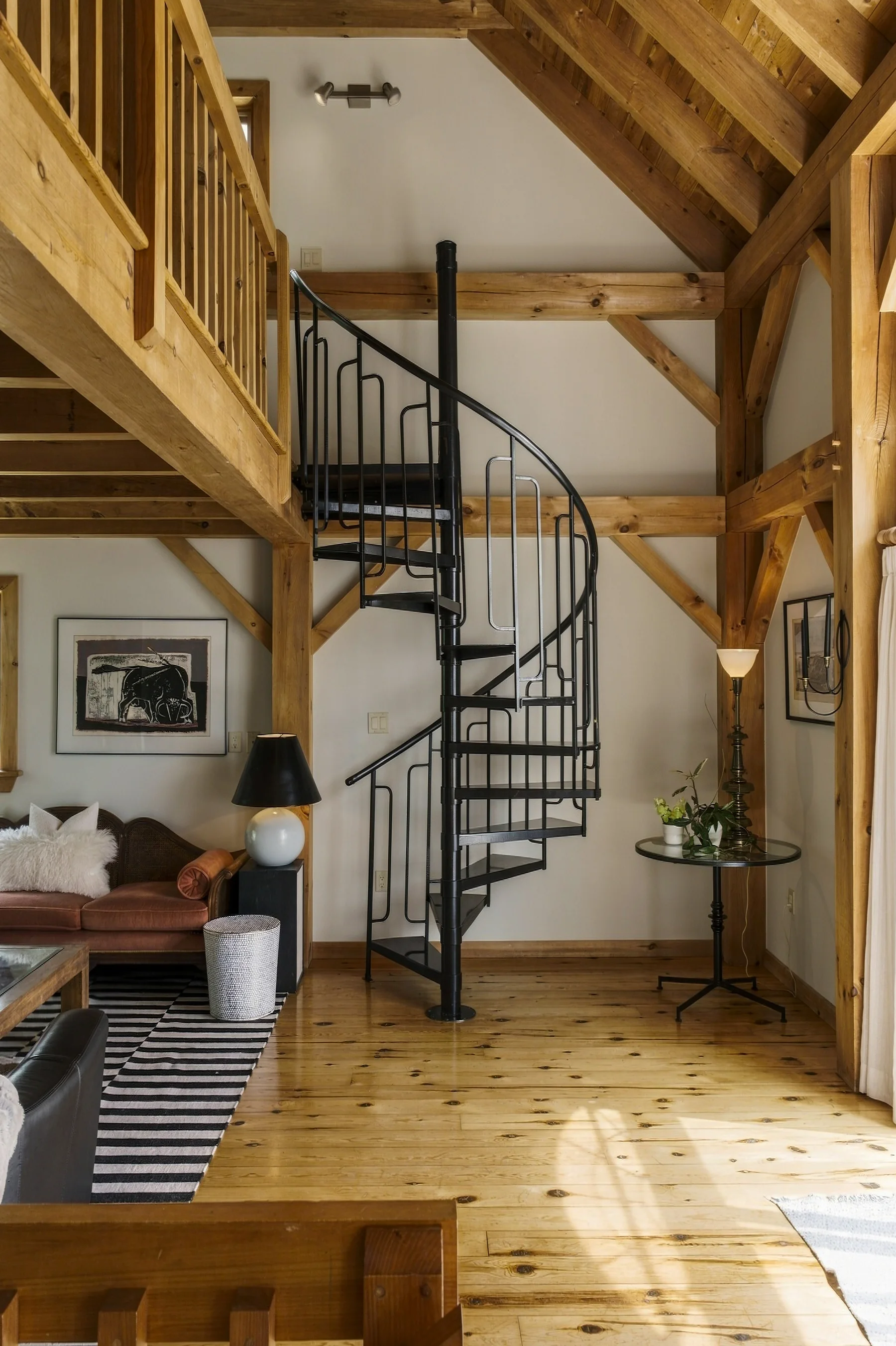 A black spiral staircase within an exposed-timber interior
