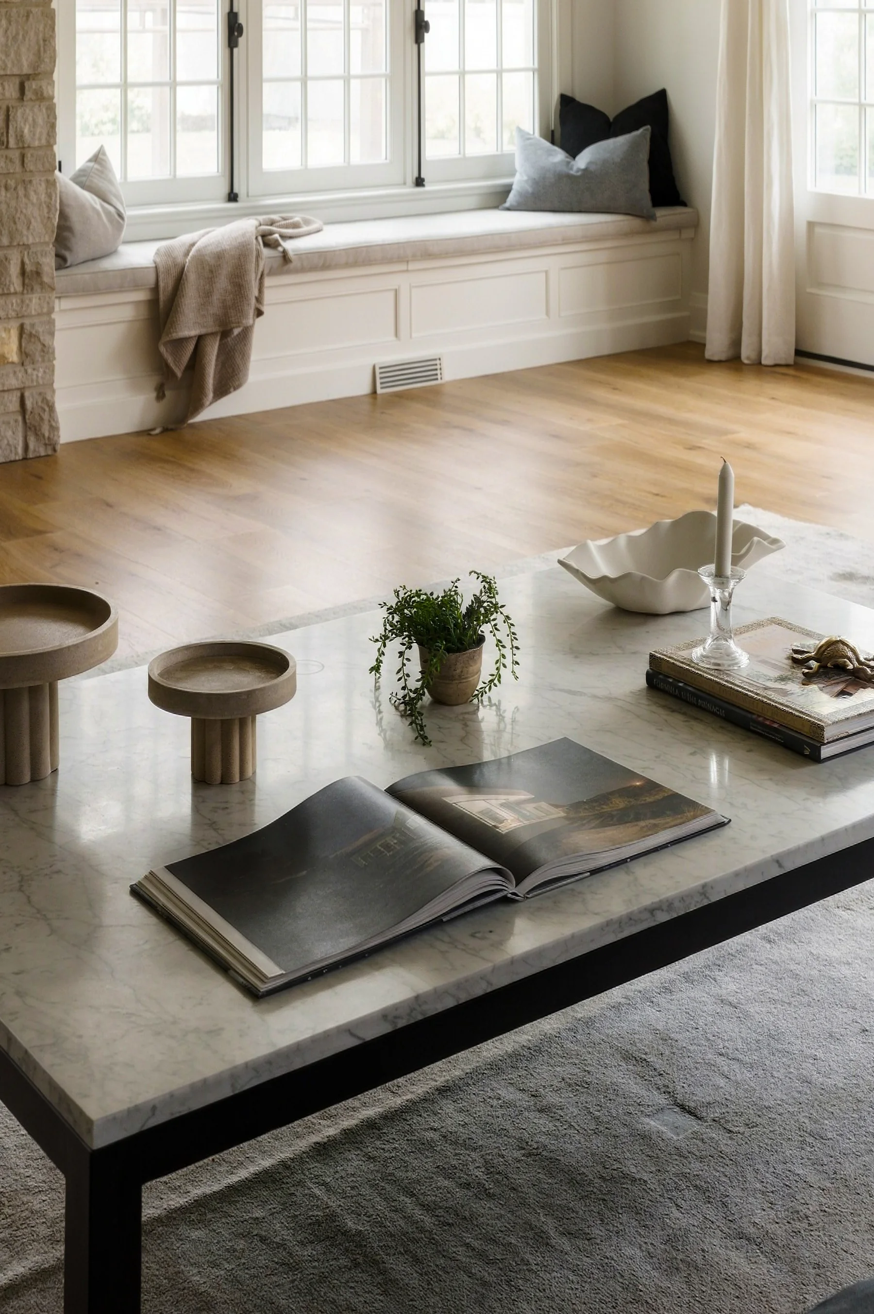 A marble coffee table and carefully arranged objects beside a window seat