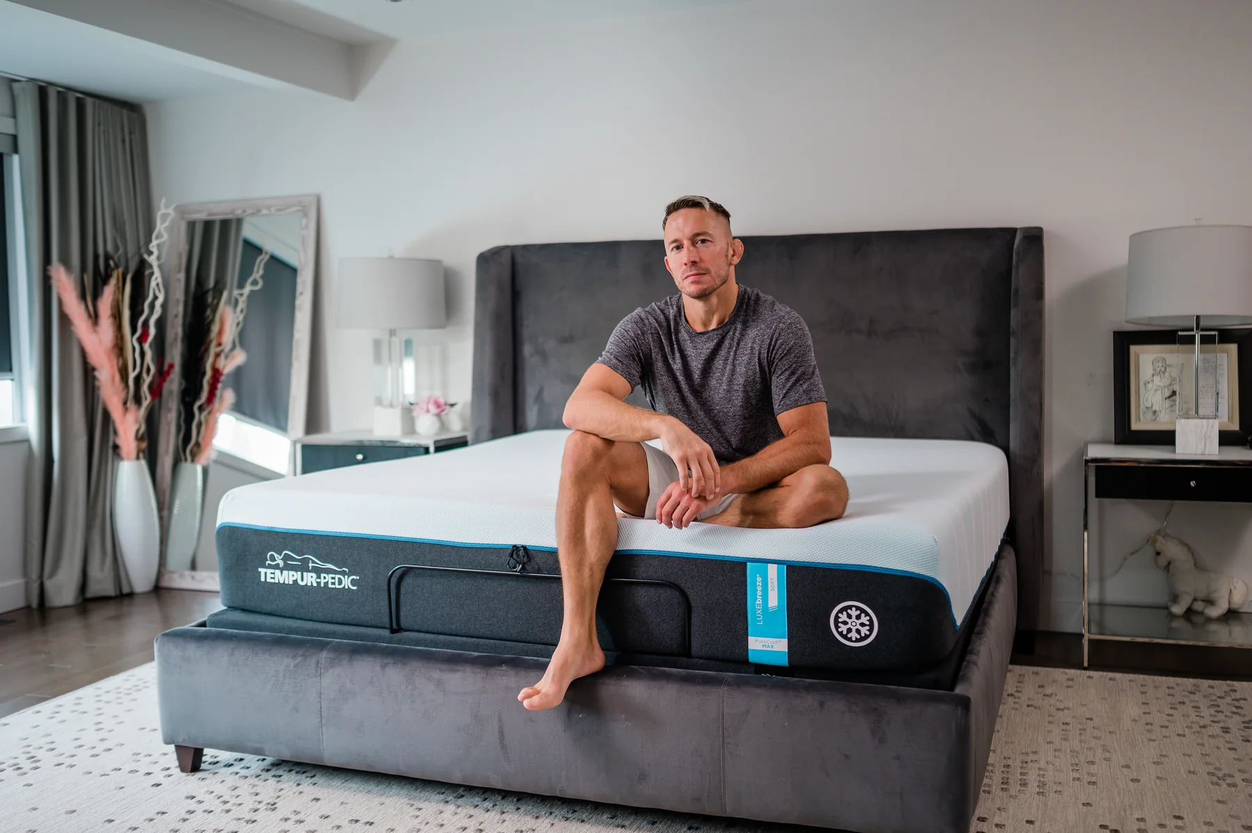A man seated on a mattress in a softly lit bedroom