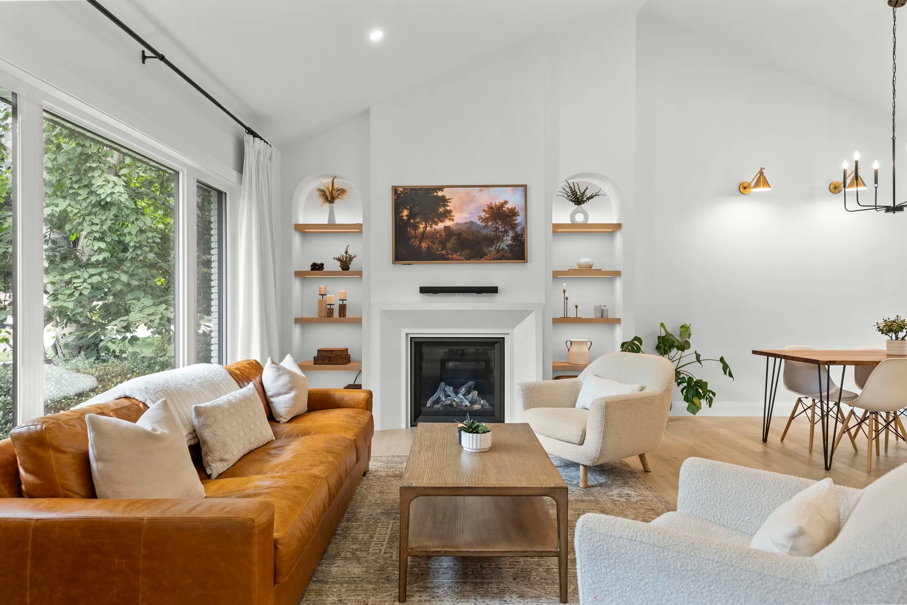 A bright living room with a fireplace, warm leather sofa and garden views